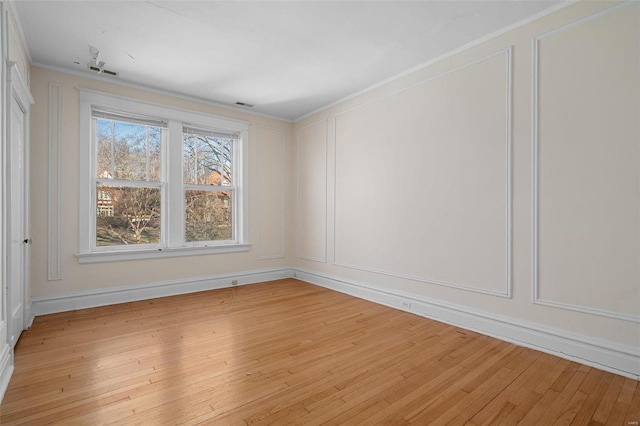6954 Kingsbury Blvd, University City, MO 63130 - unfurnished room featuring a decorative wall, ornamental molding, and light wood-style floors