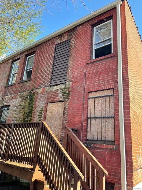 back of property with brick siding, stairs, and a deck