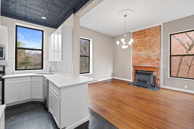 4361 Laclede Ave, Saint Louis, MO 63108 - kitchen with a sink, a peninsula, light countertops, backsplash, and open floor plan