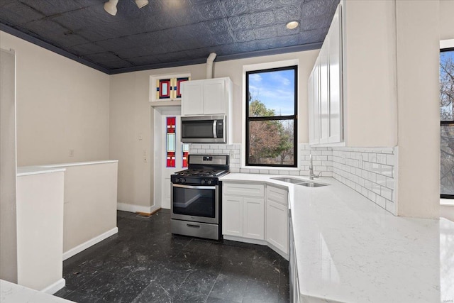 4361 Laclede Ave, Saint Louis, MO 63108 - kitchen featuring stainless steel appliances, a sink, decorative backsplash, white cabinetry, and baseboards