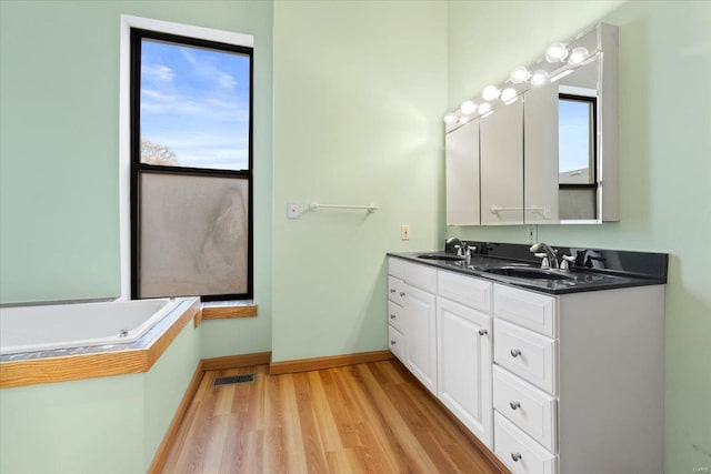 4361 Laclede Ave, Saint Louis, MO 63108 - bathroom with wood finished floors, double vanity, baseboards, and a bath