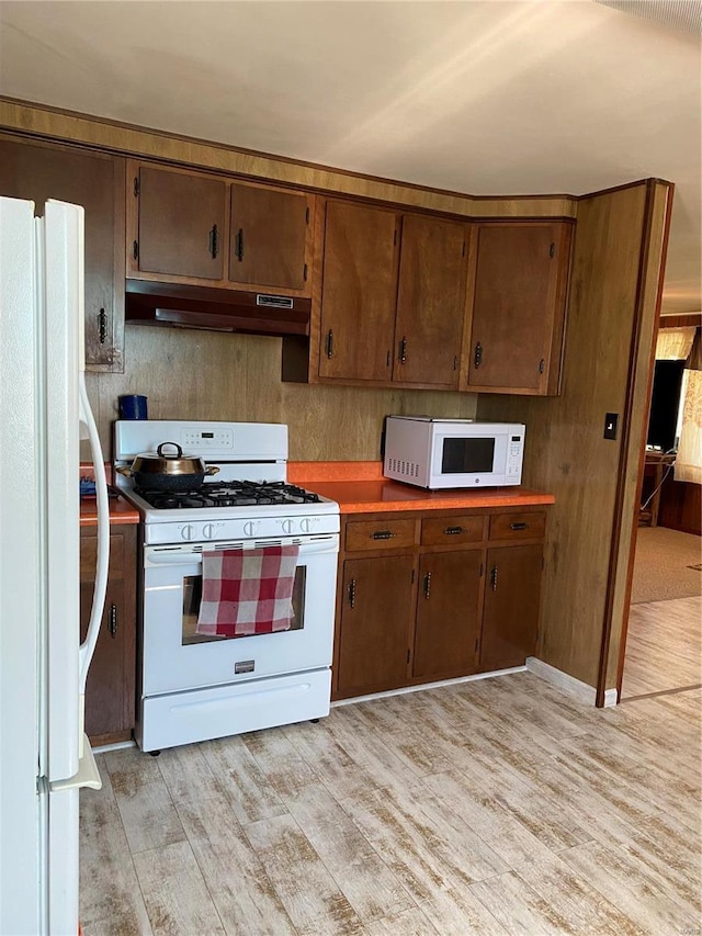 kitchen featuring white appliances, under cabinet range hood, and light wood finished floors