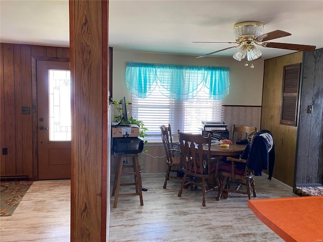 dining room with wooden walls, wood finished floors, plenty of natural light, and ceiling fan