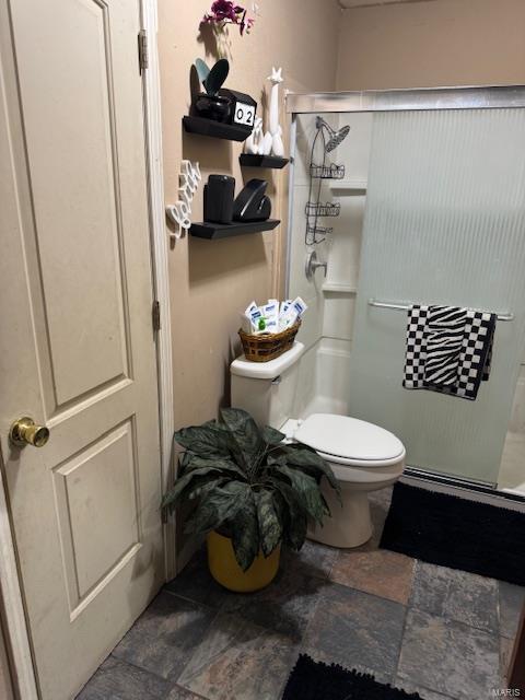 full bath with a shower stall, toilet, and stone finish floors