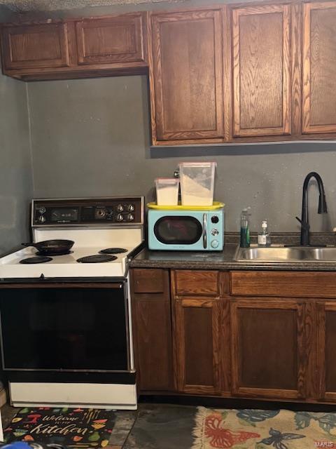 kitchen featuring electric range oven, a sink, and dark countertops