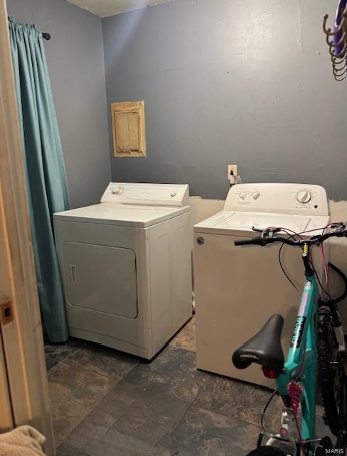 clothes washing area with separate washer and dryer and stone finish flooring
