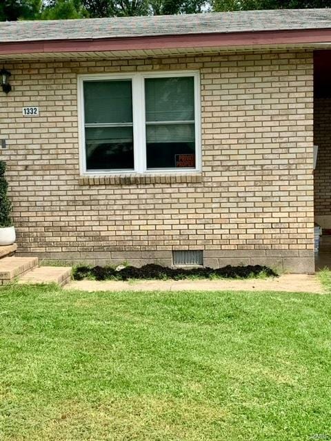 view of side of property with brick siding and a lawn