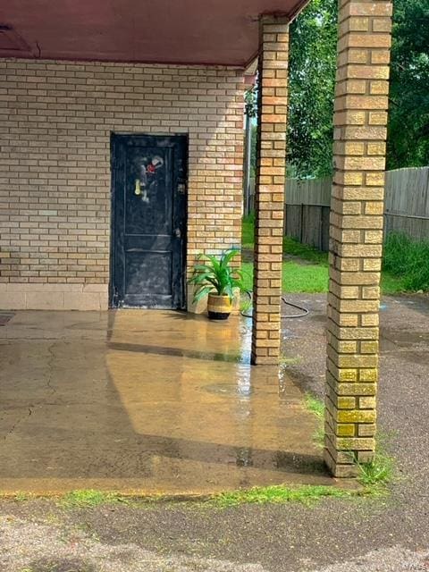 property entrance with brick siding and fence