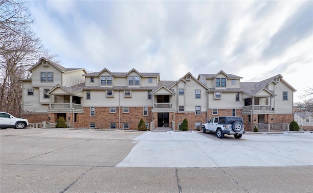 view of front of house with uncovered parking and brick siding