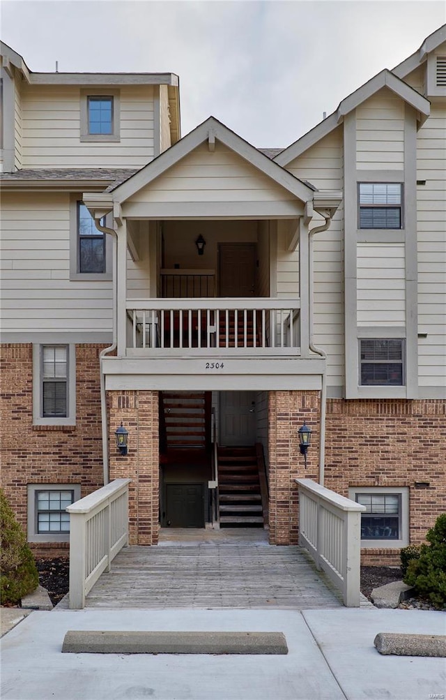 multi unit property with a balcony, brick siding, and concrete driveway