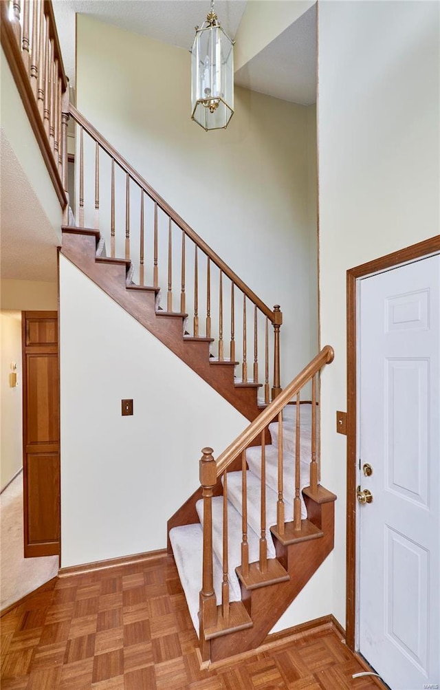 stairs featuring a chandelier and baseboards