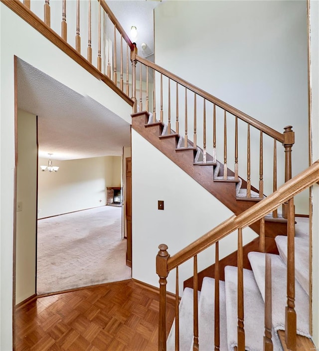 staircase with carpet flooring, baseboards, and a chandelier