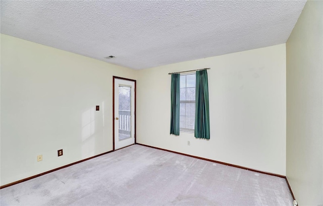 spare room featuring carpet, baseboards, and a textured ceiling