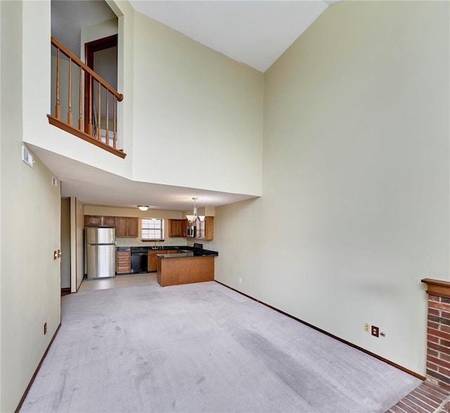 unfurnished living room with high vaulted ceiling, baseboards, a chandelier, light carpet, and a sink