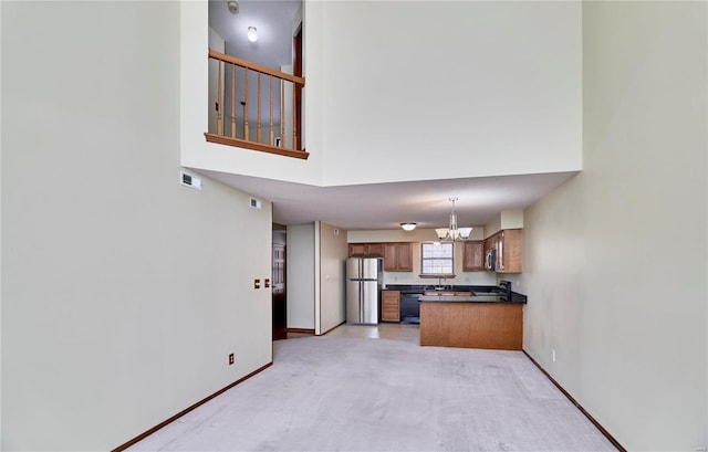 kitchen featuring appliances with stainless steel finishes, a chandelier, dark countertops, brown cabinets, and light colored carpet