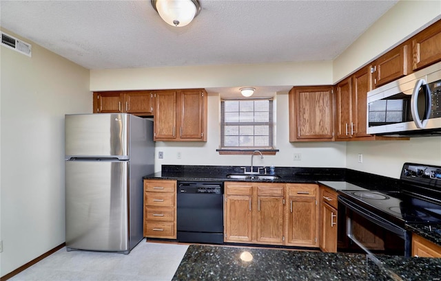 kitchen featuring black appliances, a sink, a textured ceiling, and brown cabinets