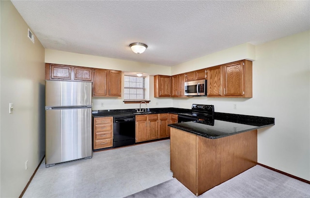 kitchen with black appliances, a sink, a peninsula, brown cabinets, and baseboards