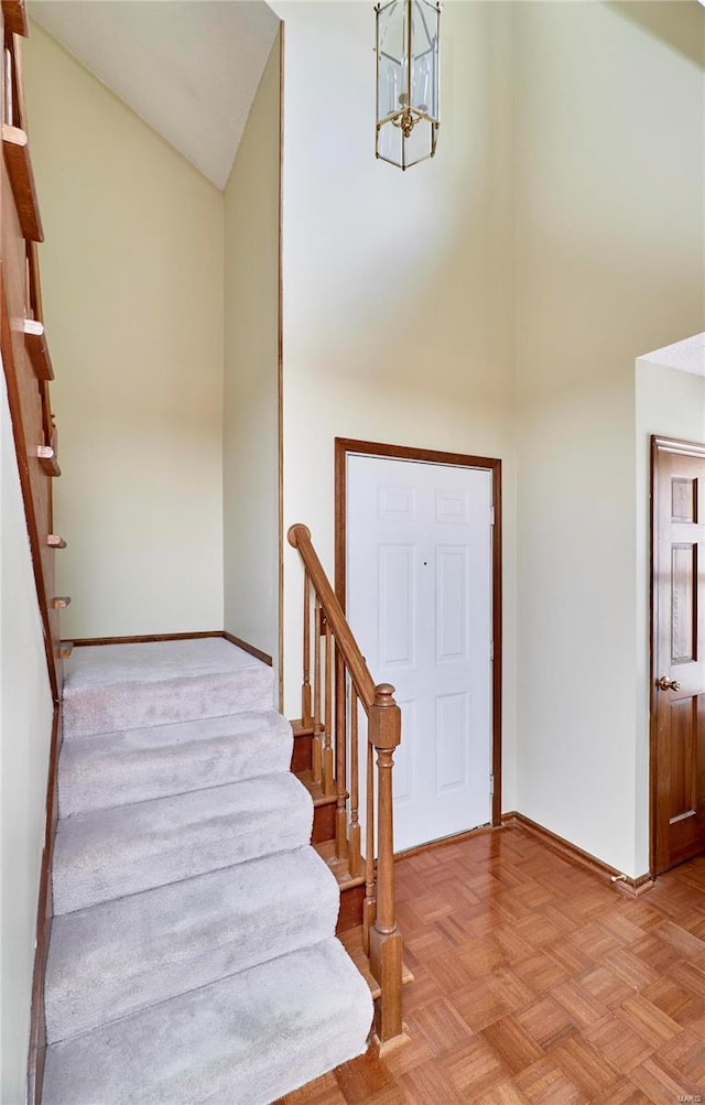 foyer entrance featuring high vaulted ceiling, baseboards, a chandelier, and stairs