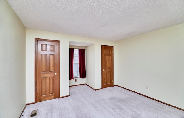 unfurnished room featuring light colored carpet, baseboards, and a textured ceiling