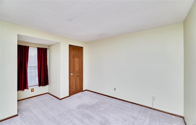 unfurnished room with carpet flooring, baseboards, and a textured ceiling