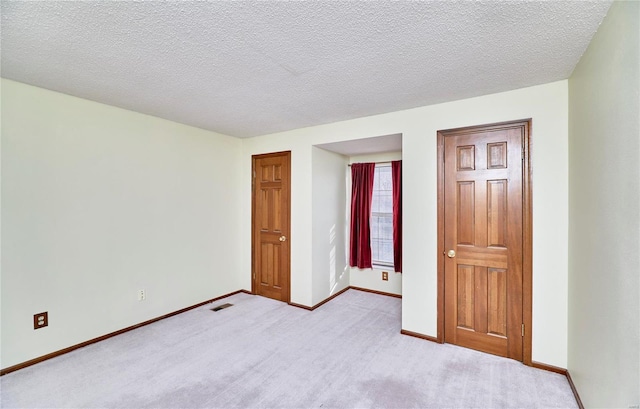 unfurnished room with baseboards, light colored carpet, and a textured ceiling