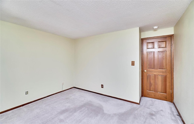 spare room with light carpet, baseboards, and a smoke detector
