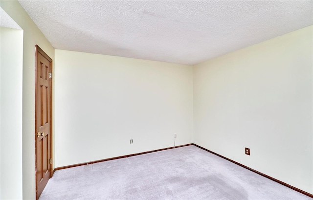 carpeted empty room with baseboards and a textured ceiling