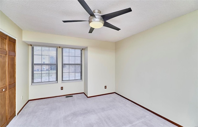 unfurnished bedroom with light carpet, baseboards, a textured ceiling, a closet, and ceiling fan