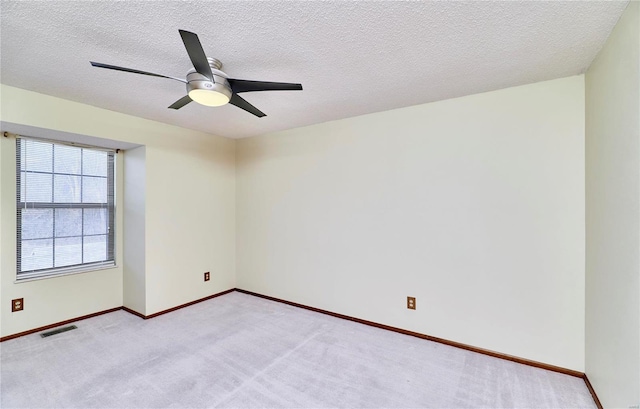 spare room with light colored carpet, a ceiling fan, baseboards, and a textured ceiling