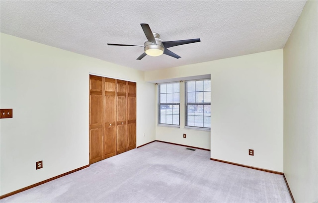 unfurnished bedroom with a closet, baseboards, carpet flooring, a textured ceiling, and ceiling fan