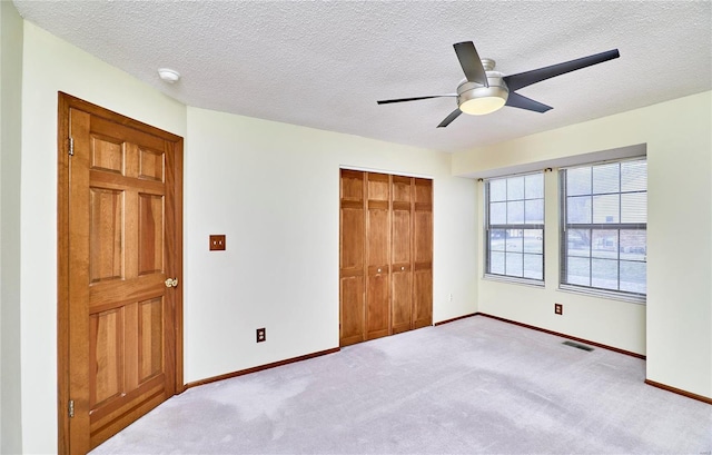 unfurnished bedroom with carpet, a closet, baseboards, a ceiling fan, and a textured ceiling