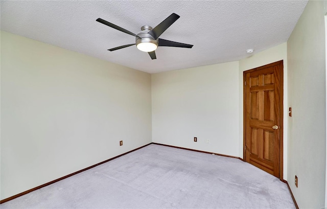 empty room featuring ceiling fan, light colored carpet, baseboards, and a textured ceiling