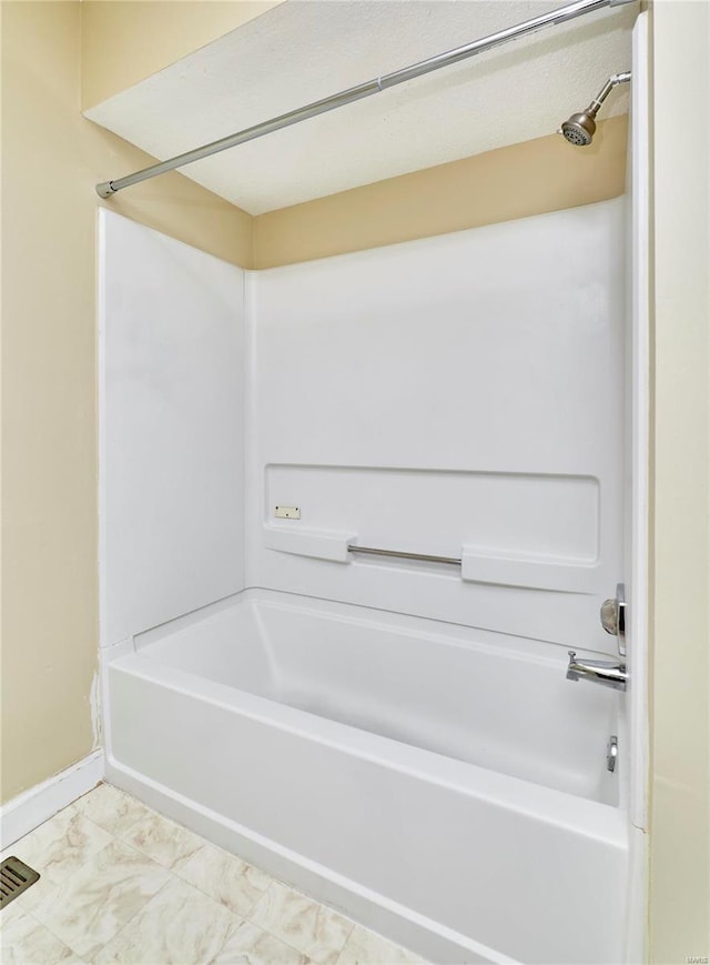 bathroom featuring baseboards and tub / shower combination