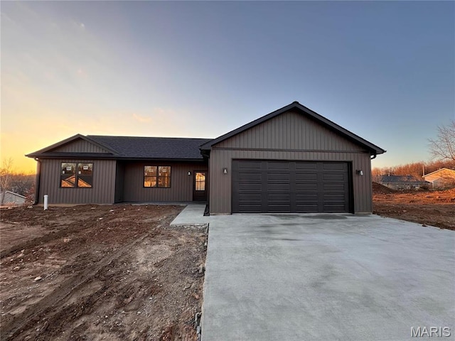 view of front of home with driveway, an attached garage, and a shingled roof