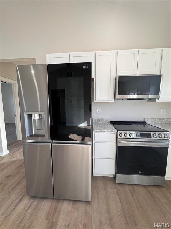 kitchen featuring appliances with stainless steel finishes, light wood-type flooring, and white cabinets
