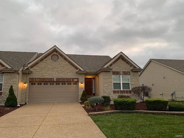 view of front of property featuring stone siding, concrete driveway, a garage, a front yard, and roof with shingles