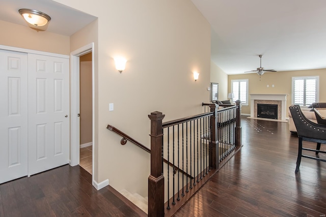 hall featuring an upstairs landing, wood-type flooring, and baseboards