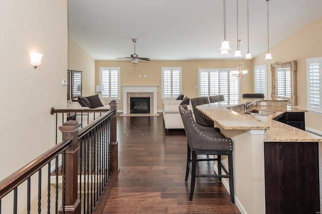 kitchen with a sink, dark wood-style floors, a ceiling fan, a breakfast bar, and lofted ceiling