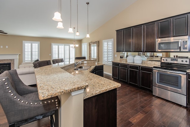 kitchen featuring stainless steel appliances, a sink, a kitchen breakfast bar, dark wood-style floors, and a chandelier