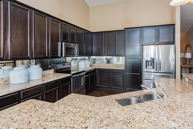 kitchen with appliances with stainless steel finishes, a sink, light stone counters, and dark wood-style flooring