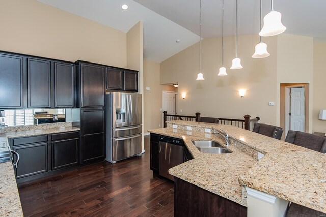 kitchen with appliances with stainless steel finishes, a sink, high vaulted ceiling, a breakfast bar, and dark wood finished floors