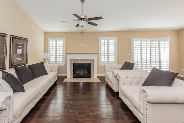 living room with ceiling fan, a high end fireplace, dark wood finished floors, and baseboards