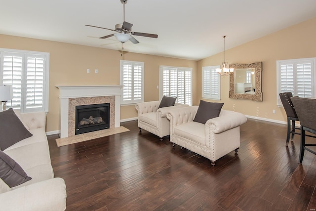living area featuring a ceiling fan, wood finished floors, a chandelier, a fireplace, and lofted ceiling