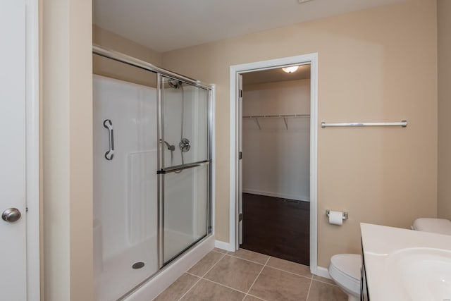 full bathroom with a shower stall, tile patterned floors, toilet, and baseboards