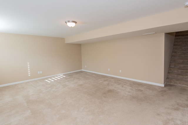 finished below grade area featuring baseboards and light carpet