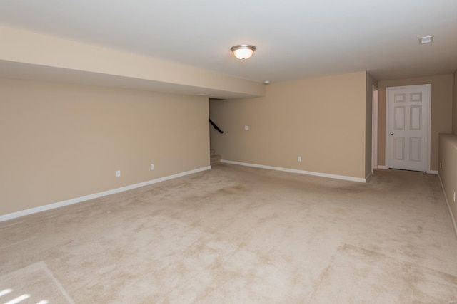 finished basement featuring baseboards, stairway, and light colored carpet