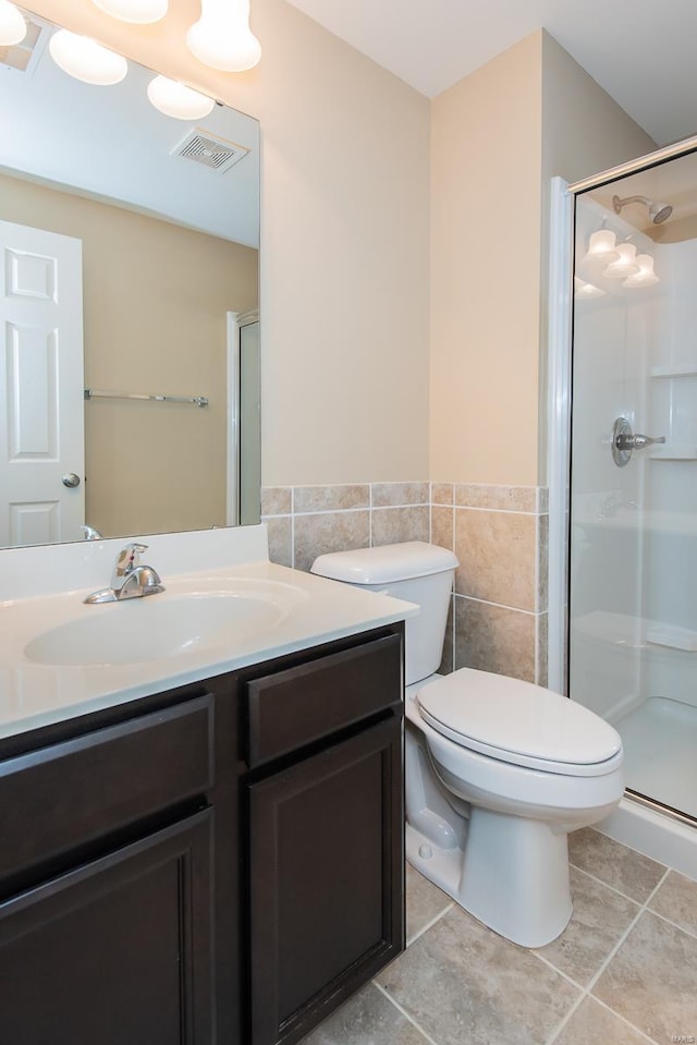 bathroom featuring a shower stall, tile walls, vanity, toilet, and a wainscoted wall