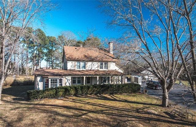 view of front of house with a chimney, a front lawn, and covered porch