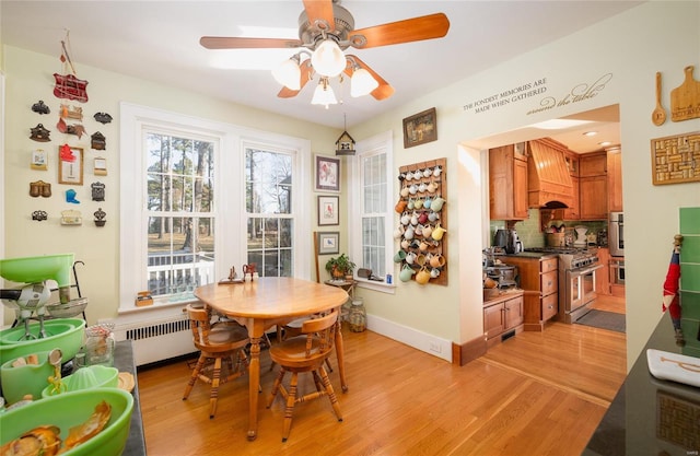 dining room featuring ceiling fan, light wood finished floors, radiator heating unit, and baseboards
