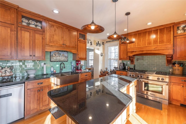 kitchen with appliances with stainless steel finishes, a sink, brown cabinets, decorative backsplash, and a kitchen island